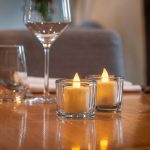 2 waxinelichtjes van dorsetto met op de achtergrond een wijnglas 