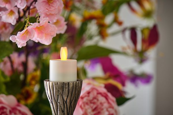 dorsetto waxinelichtje op houden in de achtergrond zijn rode bloemen te zien 