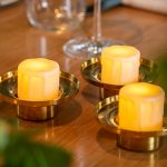 3 waxinelichtjes met kaarsvet in houders op tafel 