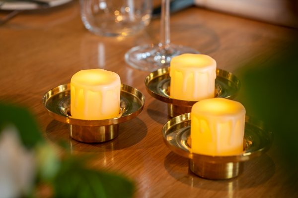 3 waxinelichtjes met kaarsvet in houders op tafel 